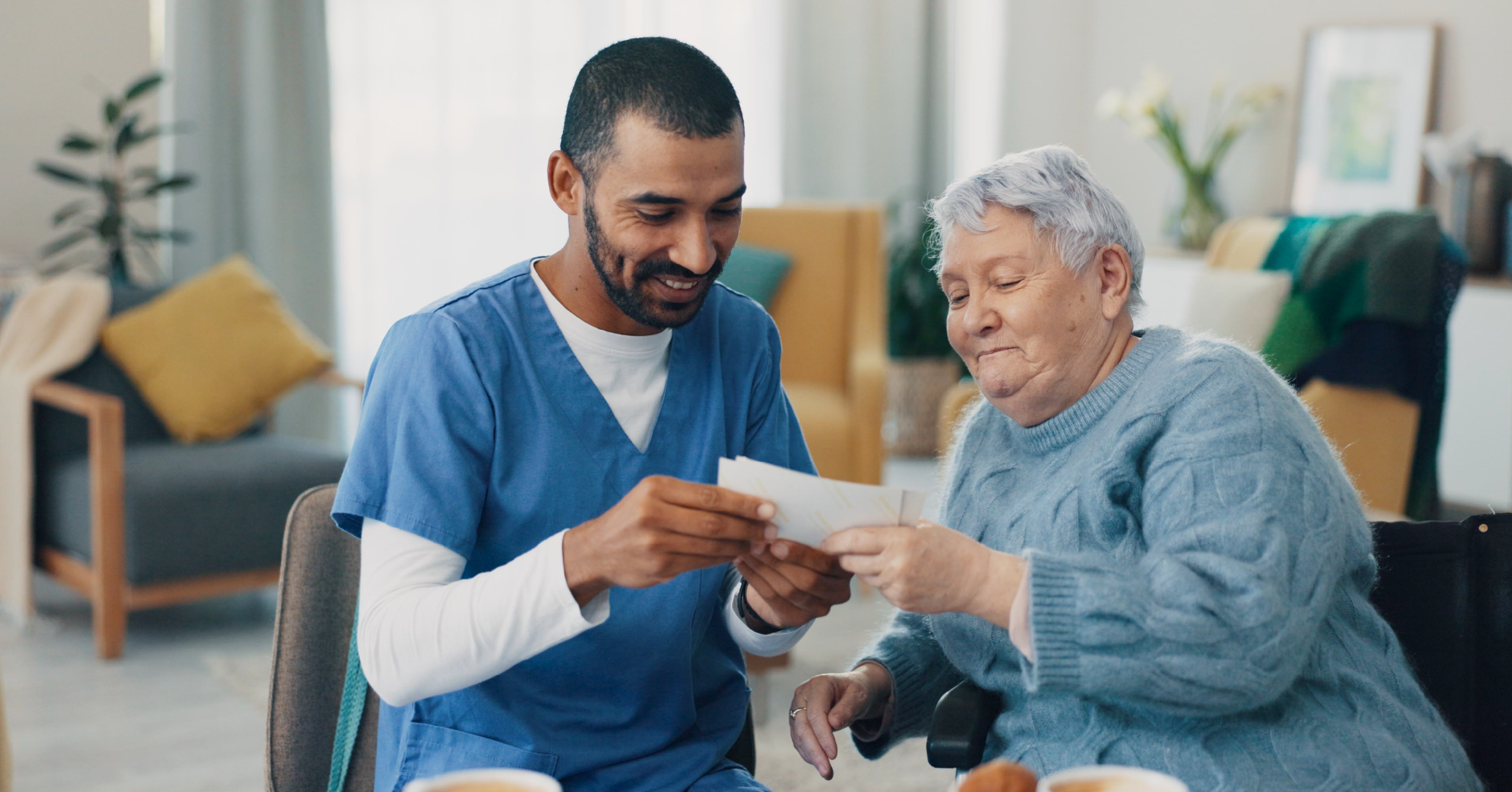 A home health care provider and an older person look together at information on a paper they are both holding.