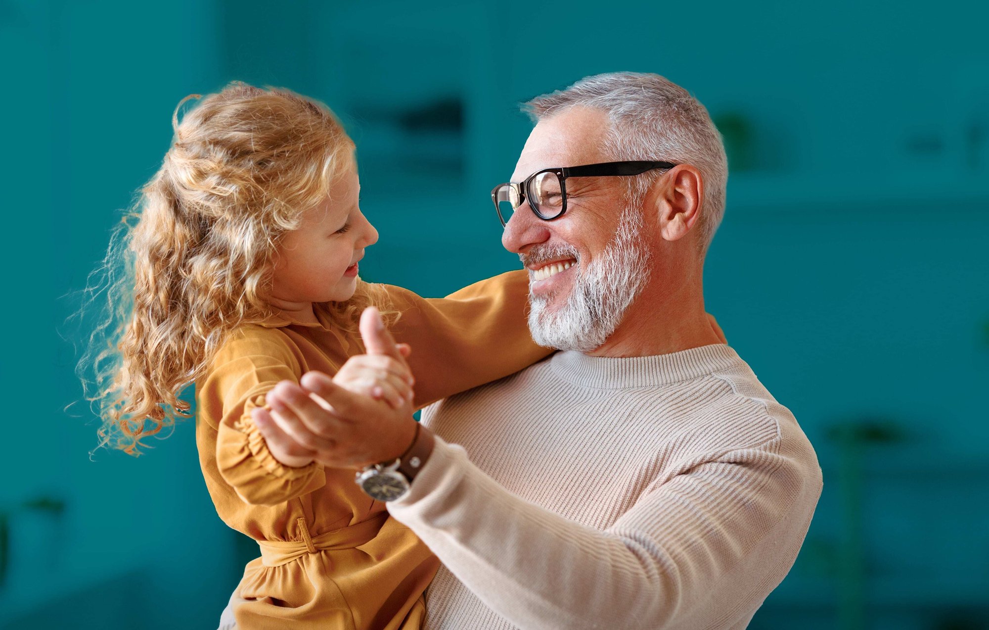 Photo of a grandfather smiling and dancing with granddaughter