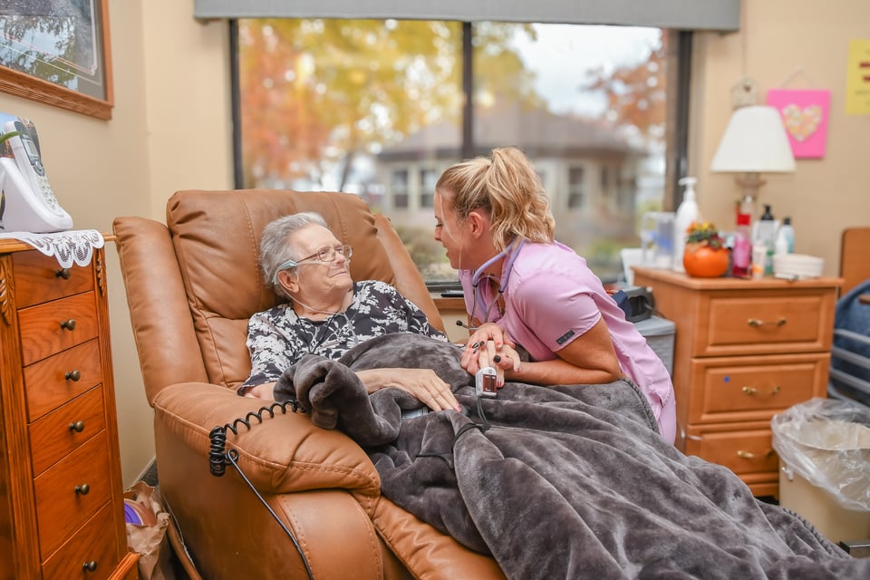 nurse kneeling to help woman in chair