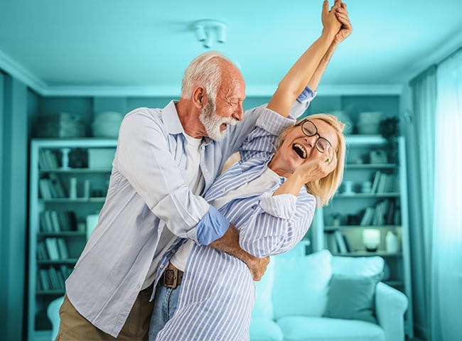 Photo of an older couple dancing in their senior living apartment