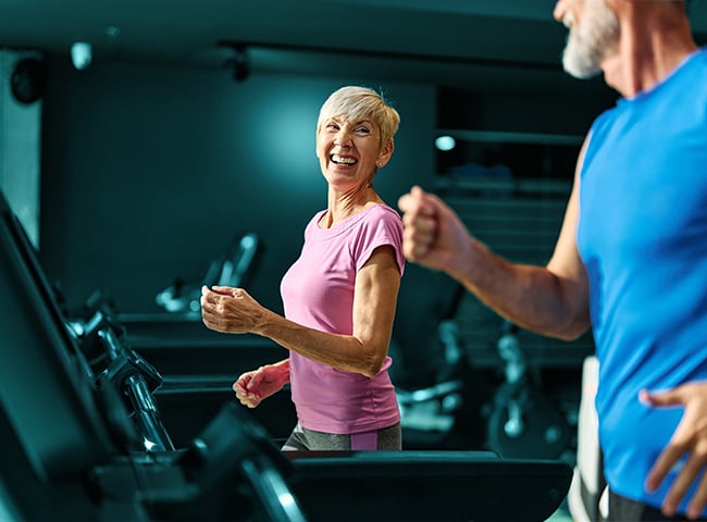 Photo of a woman and man running on treadmills