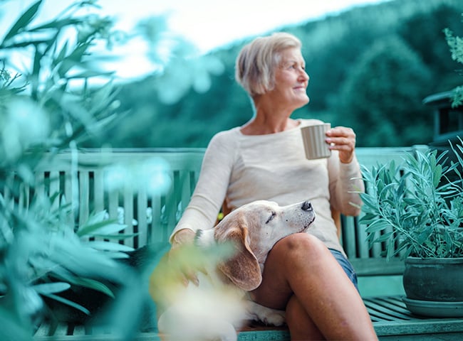 Photo of a woman drinking coffee with dog in lap