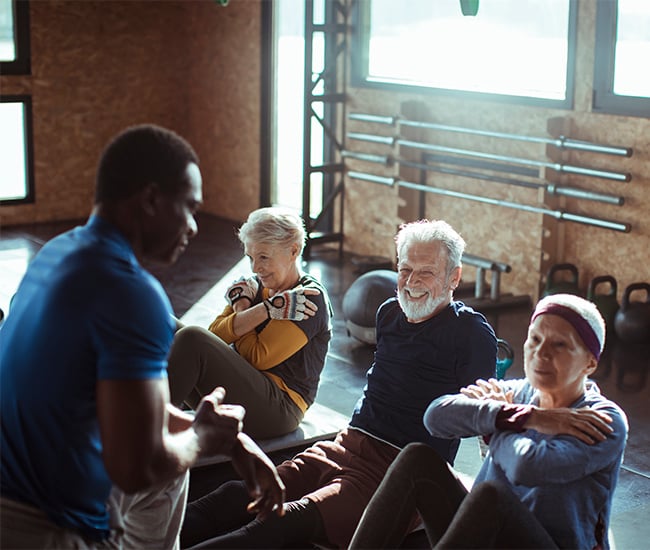 personal trainer helping older group with situps