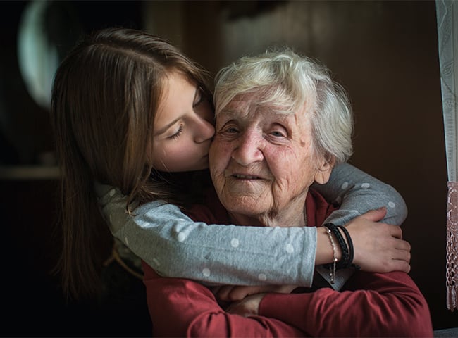 Photo of a young child hugging their grandmother