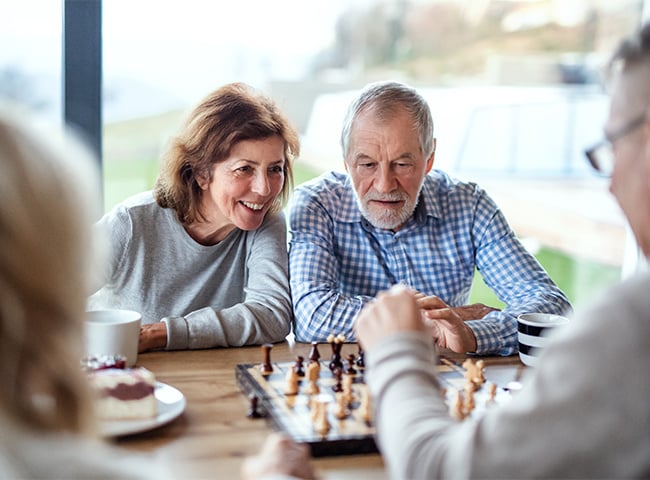 Photo of an older couple playing chess in an assisted living community