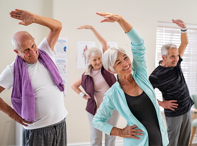 Photo of a group of adults stretching in physical rehab