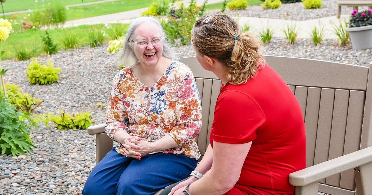 women sitting, smiling on bench