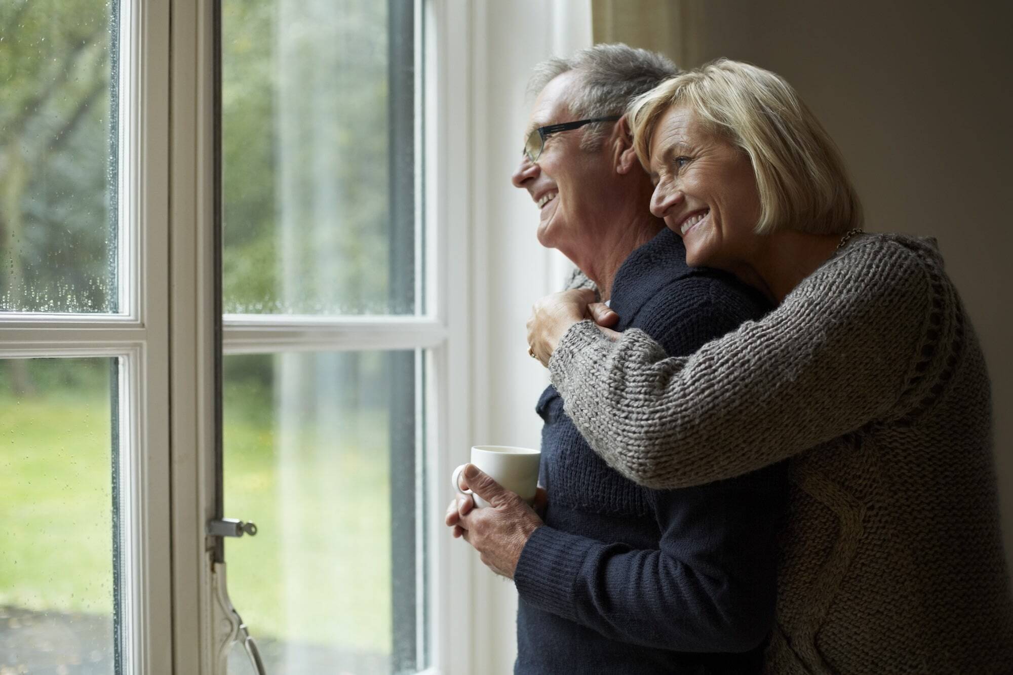 woman hugging man from behind while they look out window